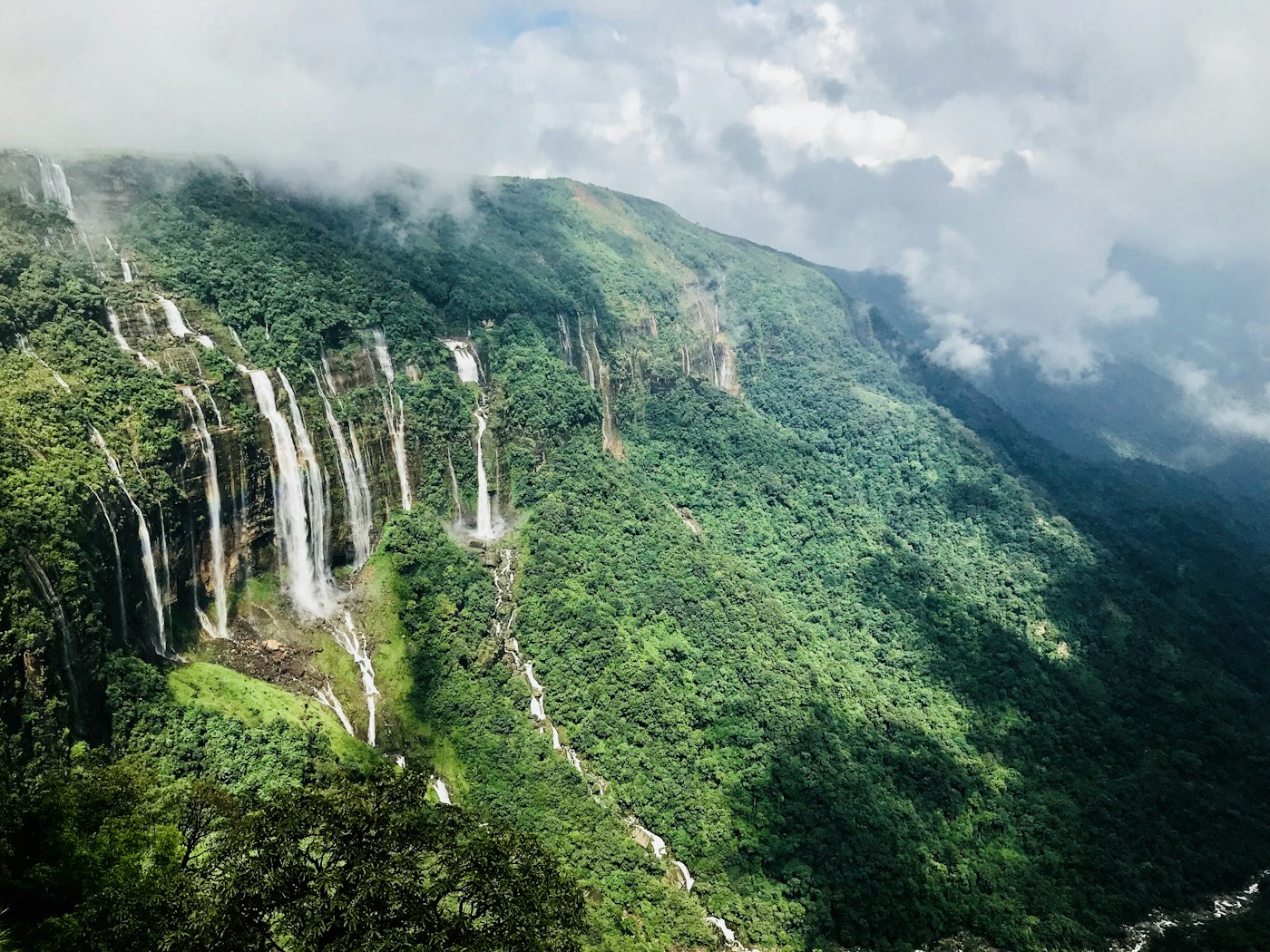 Waterfalls pouring down green cliffs in Meghalaya