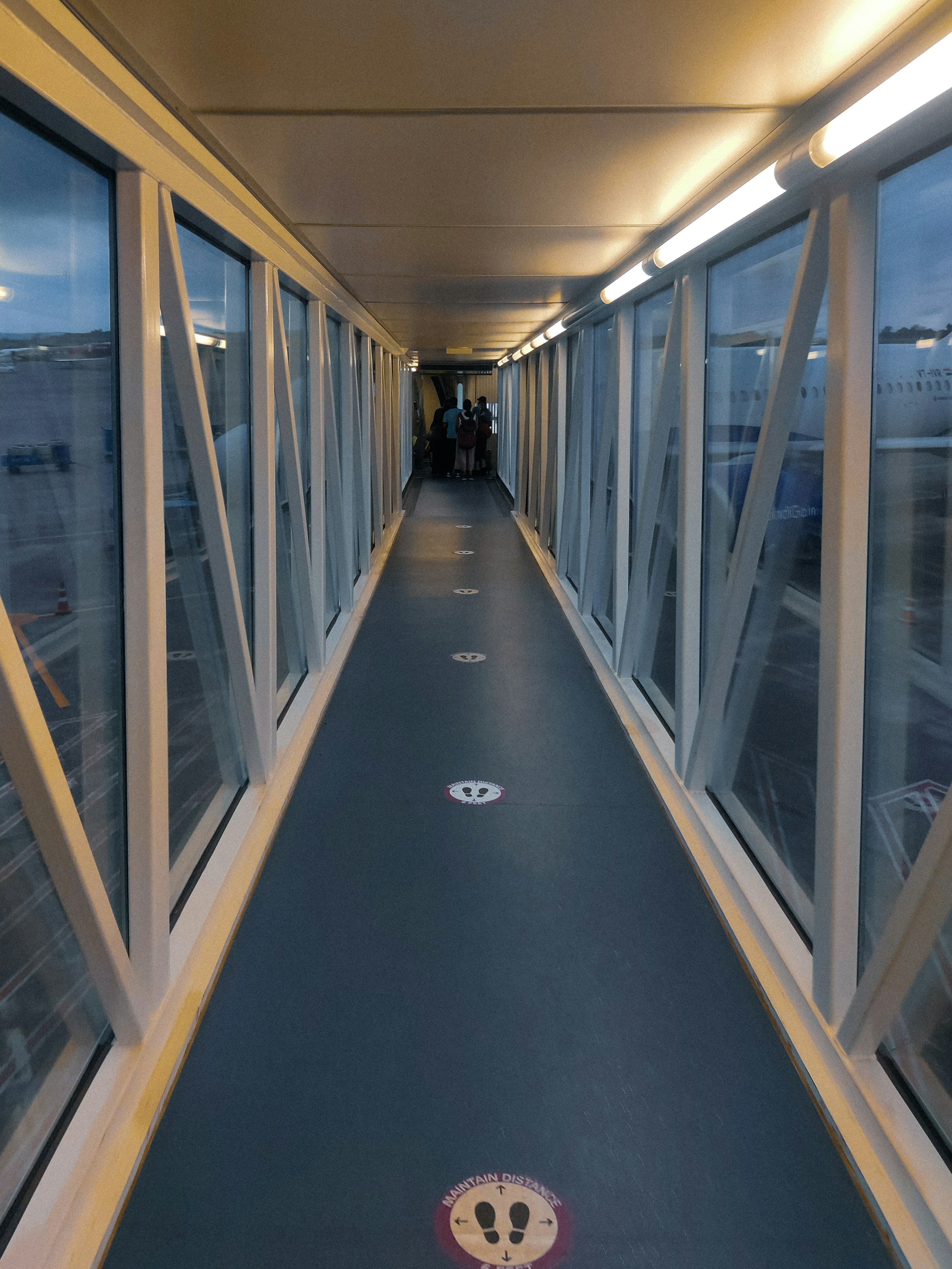 A glass jet bridge leading to the aircraft door